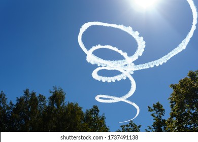 Spiral smoke trail by airplane flying in the cloudless sky on a sunny day. 