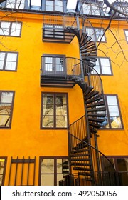 a spiral wrought-iron staircase on the background of yellow building staircase