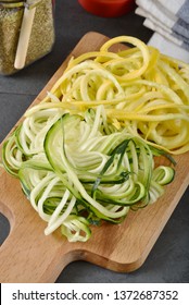 Spiralized Organic Zucchini And Yellow Squash On A Cutting Board, Vertical Composition