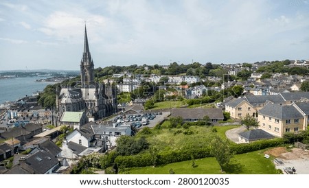 The cathedral’s spire rises like a compass needle, anchoring the whole scene, while the town curls around it in layers of colour and slate rooftops. Below, the harbour glints with that soft metallic shine you only get on calm days, dotted with boats that look almost toy‑like from the air.
