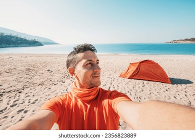 spirit of adventure along the Lycian Way as a man hiker taking selfie photo against camping tent in the sandy beach, on a sea coast - Powered by Shutterstock