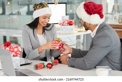 The spirit of Christmas is alive and well. Shot of a young businessman and businesswoman exchanging Christmas gifts in a modern office. - Powered by Shutterstock