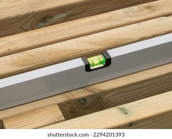 Spirit level checking the level of a plank of wood. Close up image. - Shutterstock ID 2294201393