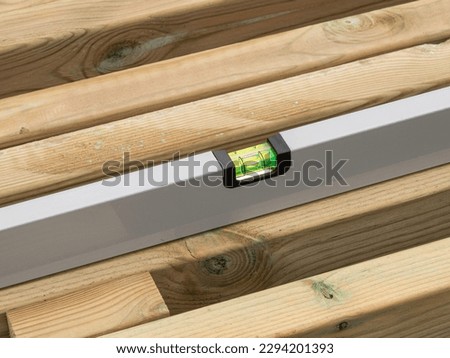 Spirit level checking the level of a plank of wood. Close up image.
