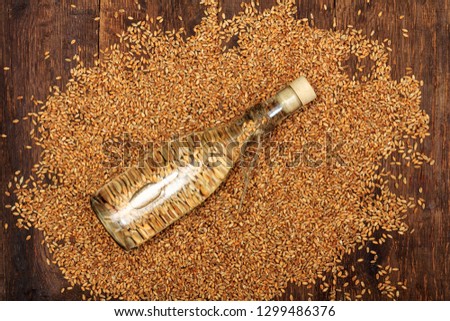 Spirits from wheat in shot glass with wheat grains and ears over rustic background