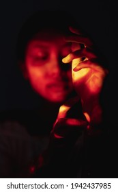 Spiritual Ritual. Sacred Ceremony. Tribal Healing. Ethnic Culture. Mistic Native Indian Shaman Woman Face Silhouette With Hand In Red Orange Light Isolated On Defocused Black Night Background.