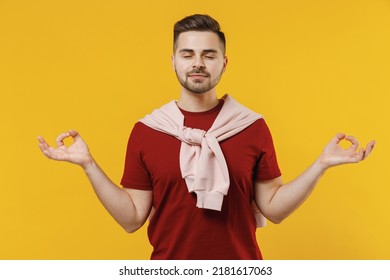 Spiritual Tranquil Young Man 20s In Red T-shirt Casual Clothes Hold Spreading Hands In Yoga Om Aum Gesture Relax Meditate Try Calm Down Isolated On Plain Yellow Color Wall Background Studio Portrait