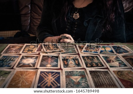 Spiritual wicca witch reading occult mystic old tarot cards on table for a magical pagan ritual psychic destiny reading - Concept of supernatural, witchcraft, destiny and mystical fortune-telling.