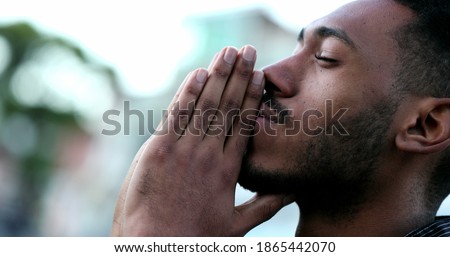 Spiritual young black African man praying to GOD. Person looking to sky with HOPE and FAITH