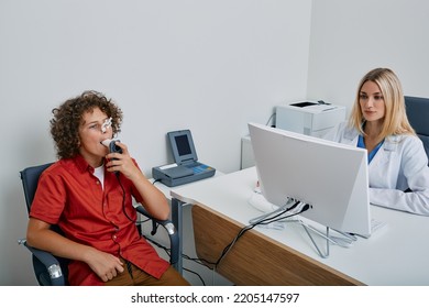 Spirometry Of Child's Lungs. Cute Boy With Female Doctor During Spirography Test And Measuring Ventilation Of Kid Lungs With Spirometer At Medical Clinic