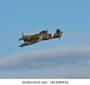 Spitfire Plane Flying In Blue Sky With Some Cloud