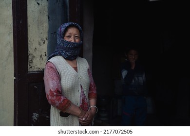 Spiti, Himachal Pradesh - 29 June 2022 - A mid aged tibbetian, himachali woman standing on the doorway to welcome with her son. Himachal and Spiti tourism.