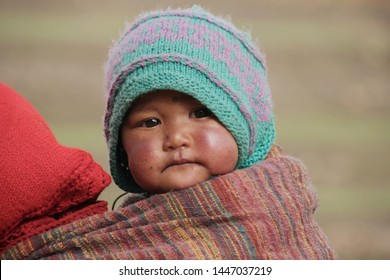 Spiti valley, India - May 13, 2014: Tibetan baby portrait . Colourful dressed Little child carried in a sling.