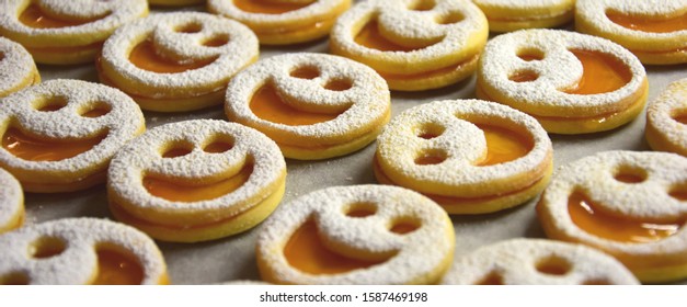 Spitzbuben - Delicious Christmas Cookies With A Laughing Face - Biscuits With Apricot Jam And Icing Sugar As Background Or Texture And Banner At Christmas Time