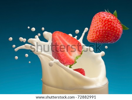 Splash of milk, caused by falling into a ripe strawberry. Isolated on a blue background.