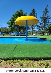 A Splash Pad With Water Raining Down From A Large Umbrella At The End Of A Pool Area.