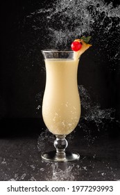 Splash Of Pina Colada Cocktail Decorated With A Piece Of Pineapple And Cherry On Black Background