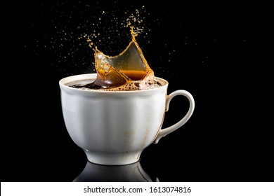 Splash And Splatter From A Piece Of Sugar In A Mug With Coffee On A Black Background