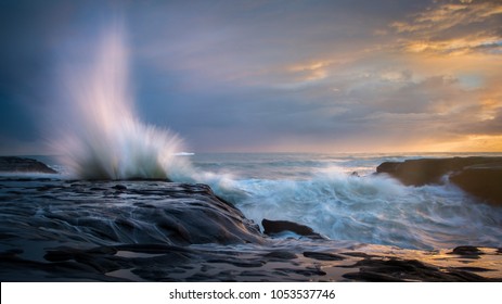 Splash waves at Sunset, at wild west coast of Auckland New Zealand