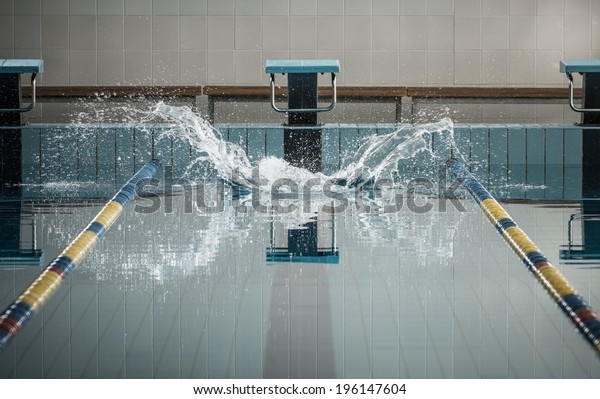 Splashes after\
swimmers jump in a swimming pool\
