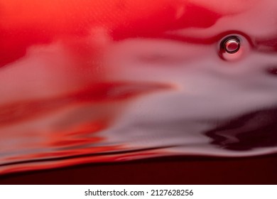Splashes, bubbles and waves from red wine in a glass