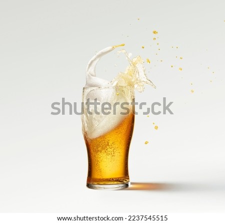 Splashes and drops. Glass of frothy light lager beer isolated over grey background. Popular drink. Concept of alcohol, oktoberfest, drinks, holidays and festivals. Copy space for ad.