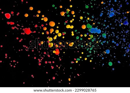 Splashes of paint on a black background. Colored spots of paint on a black background. There are many drops of colored paint on black paper.