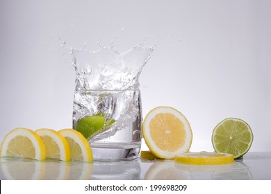 Splashes of water, lemon falling into a glass, isolated, reflection, white background 