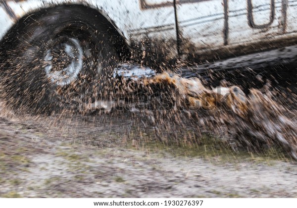 Splashes of water and mud are\
flying from under the wheels of a rushing car. Blur. Car on bad\
road. 