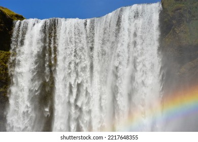 Splashes, water and a rainbow at the Skógafoss waterfall close up in Iceland on a summer sunny day