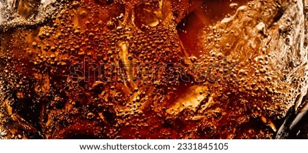 Splashing of Cola and Ice. Cola soda and ice splashing fizzing or floating up to top of surface. Close up of ice in cola water. Texture of carbonate drink with bubbles in glass. Cold drink background