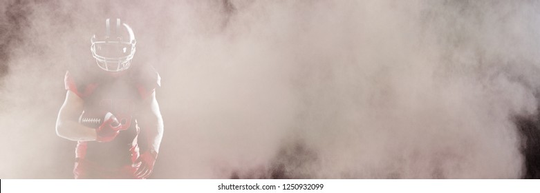 Splashing of color powder against american football player in helmet taking position against black background - Powered by Shutterstock