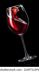 splashing red wine in falling glass isolated on black background