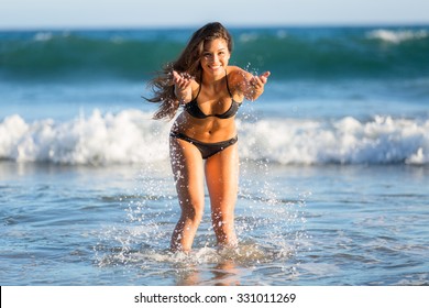 Splashing water beach ocean cute fun beautiful mixed race model perfect shape body bikini swimsuit laughing smile