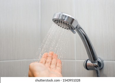 Splashing Water Close Up Background. Close-up Of A Man Hand Check Water Temperature In The Shower With Hand Shower Wall.