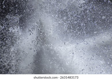 Splashing water droplets in motion against a grey background.