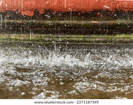 Splashing water on the floor during heavy downpour in a traditional courtyard of Coastal Karnataka, India.