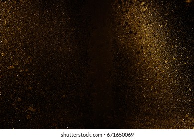 splashing water reflect light in gold. Black background.