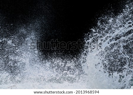 splashing water of sea wave from storm crashing on shore spraying white water foam and bubble in air isolated on black background with clipping path