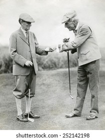 A splendid long putt deserves a dime'. John D. Rockefeller hands Harvey Firestone a dime during a golf match at Orvond Beach, Florida. Jan. 31, 1930.