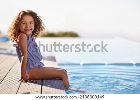 Splish Splash. Portrait of a happy little girl dipping her feet in the pool.