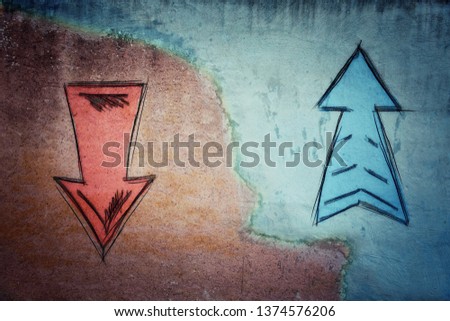 Split concrete wall cracked in the middle and arrows going in two different ways on red and blue side. Correct choice between up and down, failure or success. Difficult decision and doubt concept.