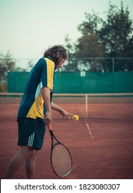 Split Croatia September 2020 Back View Of A Man Holding A Racket And A Ball, Prepairing To Serve While Playing A Match Of Tennis Outside On An Orange Clay Field