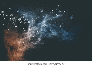 Split debris of stone exploding with blue powder against black background.