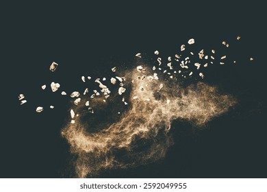 Split debris of stone exploding with brown powder against black background.