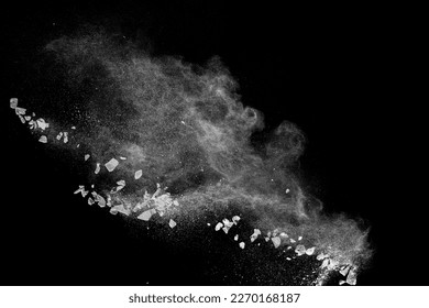 Split debris of  stone exploding with white powder against black background.
