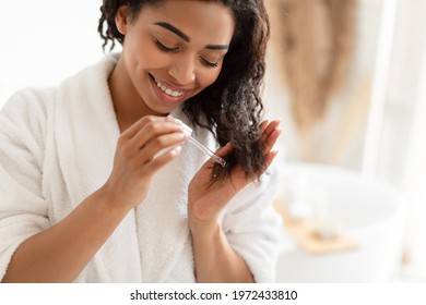 Split Ends Treatment. African American Woman Applying Serum On Damaged Dry Hair In Modern Bathroom At Home. Cosmetics For Hair Repair, Haircare And Beauty Care Routine Concept. Cropped