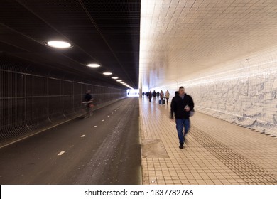 Split image: half dark, half light: Underground tunnel for pedestrians and bicycles in Amsterdam, Netherlands.