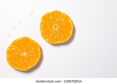 Split oranges against white background. Spilled juice drops visible