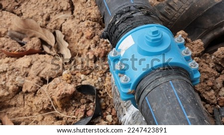 Split pipe clamp. Tapping sadder clamp is a plastic plumbing clamp with split pipe on brown clay background and copy space with selective focus.